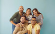 © Studio Romantic - Group portrait of five happy, smiling mixed race multi ethnic friends. Team of 5 cheerful young diverse people with toothy smiles having photoshoot and looking at camera against blue studio background