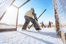 Children Play Hockey. Team Of Young Boys Are Engaged In Active Winter Sports On The Ice Of The Lake Against The Background Of A Snow Landscape On A Sunny Day. Art Photography In Retro Style.