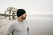 © contrastwerkstatt - Bearded man in beanie staring out over a calm winter ocean