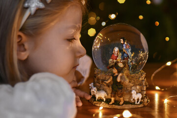 Wall Mural - Girl looking at a glass ball with a scene of the birth of Jesus Christ