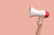 Megaphone in woman hands on a pink background.