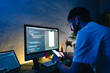 © nikkimeel - Young man mobile developer writes program code on a computer and check app in smartphone, programmer work in home office.
