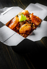 Wall Mural - Fried rice with shrimp and vegetables in paper box on wooden table background