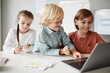 © Seventyfour - Group of children sitting at the table and typing on laptop during a lesson, they studying online