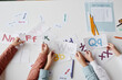 © Seventyfour - Close-up of children sitting at the table together with cards and learning English alphabet