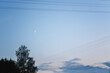 evening clear sky with a moon between the electrical wires, with clouds below