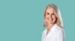 © jutaphoto - Attractive elderly woman with gray hair in casual clothes posing on a light blue green background in the studio. Makeup and senior elderly skin care. Portrait of business woman smiling
