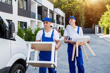 Two removal company workers are loading boxes and furniture into a minibus.