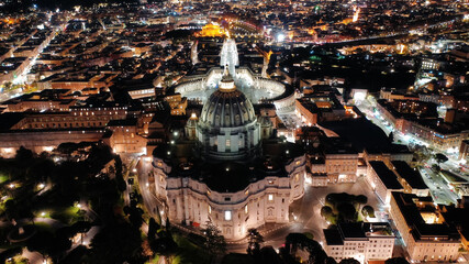 Wall Mural - Aerial drone night shot of iconic masterpiece Saint Peter Basilica and whole illuminated city of Vatican the biggest church in the world, Metropolitan city of Rome, Italy