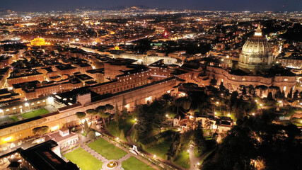 Wall Mural - Aerial drone night shot of iconic masterpiece Saint Peter Basilica and whole illuminated city of Vatican the biggest church in the world, Metropolitan city of Rome, Italy