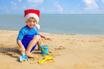 Wall Mural - happy child boy in santa hat playing with toys for sand