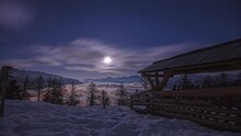 Night Timelapse Over Winter Altitude Mountains On Italian Alps. Moonlight Brightens The Scene, Clouds Carpet