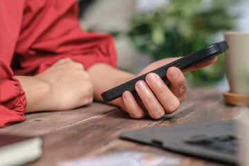 close up woman hand using credit card shopping online on mobile app on wood table at home