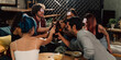 © twinsterphoto - Diverse group of young people partying and toasting a drink in the house enjoying nightlife. Multiethnic friendship and social gathering concept.