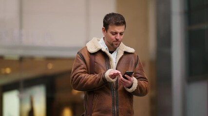 Wall Mural - slow motion of handsome Caucasian businessman walking out of office building using mobile phone browsing online urban people lifestyles with Mobile Internet