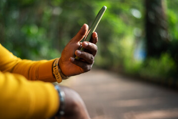 a person using a smartphone on green bokeh background, male hand holding a smartphone