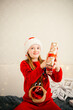 © Анна Молько - cute little girl in red sweater and santa claus hat rejoices with gifts for christmas. sincere joy and happiness. children's open emotions
