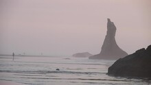 A Photographer Captures A Picture Of Rock Stacks In The Mist Of An Oregon Beach.