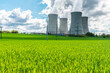 © Yuri Hoyda - Cooling tower of nuclear power plant behind green grass. Atomic energy. Nuclear power and the environment.