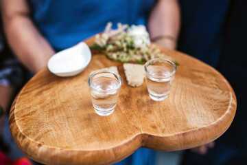 Wedding tradition in Poland and Russia. Parents welcome bride and groom with bread, vodka and salt. Decorative tray with food and alcohol. European culture background. Heart shape wooden tray.