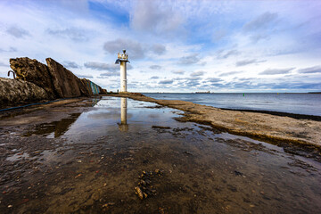 Wall Mural - a big lighthouse stands at the end of the town mole