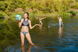 Friends play ball on a cool river on a hot summer day. Fitness and leisure concept