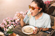 Happy asian woman eating itallian spaghetti or pasta outdoors in open restaurant. Traditional cuisine and hunger concept