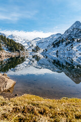 Reflection of the snowy mountains in the beautiful Baciver lake in the Pyrenees mountains of Val d'Aran (Aran Valley), Lleida, Catalonia, Spain