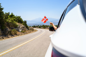 Wall Mural - Woman holding Denmark flag from the open car window driving along the serpentine road in the mountains. Concept