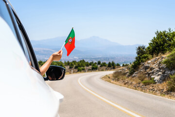 Wall Mural - Woman holding Portugal flag from the open car window driving along the serpentine road in the mountains. Concept