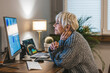 © Dragana Gordic - Focused old woman with white hair at home using PC computer. Senior stylish entrepreneur with notebook and pen wearing eyeglasses working on computer at home. Serious woman analyzing