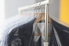Clothes In Plastic Bags Hanging On Hanger In Laundry Closeup