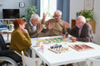 © pressmaster - Senior man winning in the board game while sitting at the table and playing with his friends
