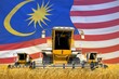 industrial 3D illustration of four orange combine harvesters on farm field with flag background, Malaysia agriculture concept