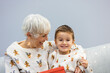 © Dragana Gordic - Happy family on Christmas morning. Affectionate grandmother and cheerful grandson open a holiday gift together at home. Happy family grandmother with cute excited grandson unpacking Christmas gift box