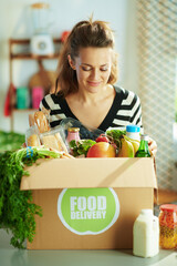 Wall Mural - smiling young female with food box in kitchen