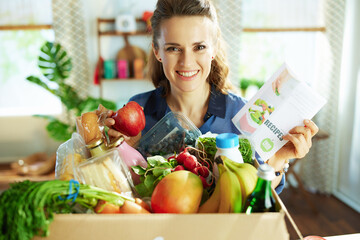 Wall Mural - smiling modern woman with food box in kitchen