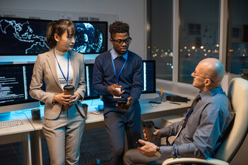 Poster - Two businessmen with smartphones and drinks discussing working points while young Asian female colleague listening to them