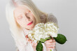 Top view of albino model in blouse holding hydrangea flower isolated on white.