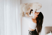 Woman kissing teddy bear in living room