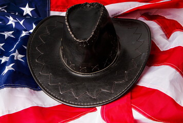 Wall Mural - black classic wide-brimmed cowboy hats on the background of the flag of the united states of america