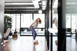© Westend61 - Smiling female professional doing skateboarding in office