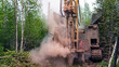 The crawler drilling rig drills well, there is a lot of dust when drilling a well. Drilling of exploration wells in the forest