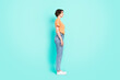 © deagreez - Photo of charming sweet young lady wear orange t-shirt standing looking empty space smiling isolated turquoise color background