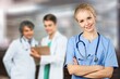 © BillionPhotos.com - Portrait of happy young nurse in uniform with healthcare team in background. Successful doctor and nurses