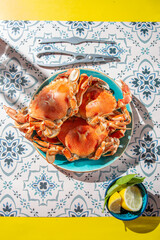 Wall Mural - Cooked crab on blue plate, lemons, rose wine on table, sunlight immitation