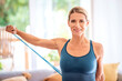 © gzorgz - Attractive woman exercising with a power band at home