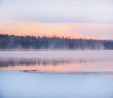 Winter Landscape, The Water Of The Lake Under The Snow Soars Against The Background Of Dawn And The Forest.