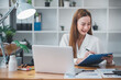 © Daenin - Asian woman sitting at a desk working in the office use a computer, laptop
