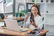 © Daenin - Excited Asian woman sitting at her desk Feel satisfied with the business going well. Very happy to receive letters from laptops and smartphones promoted at work.